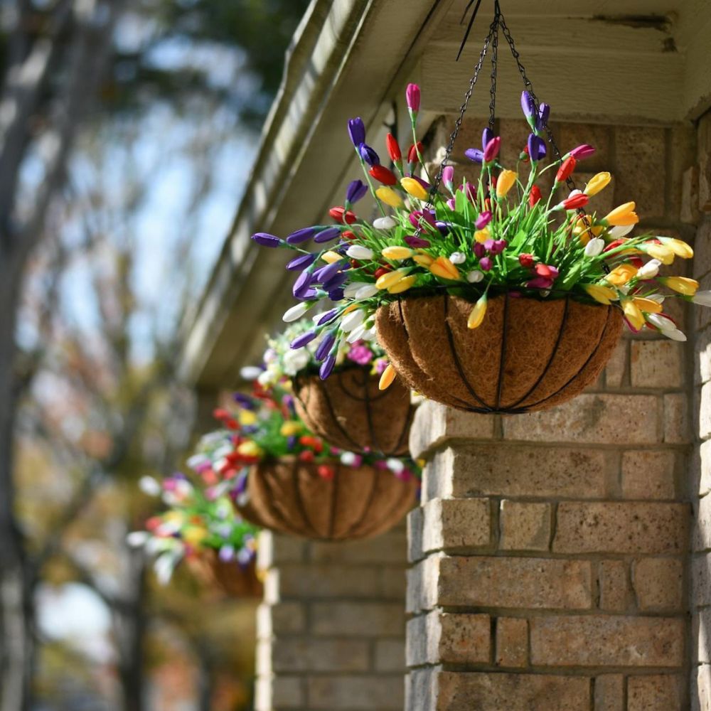 Hanging flower baskets with colorful flowers on a stone wall.