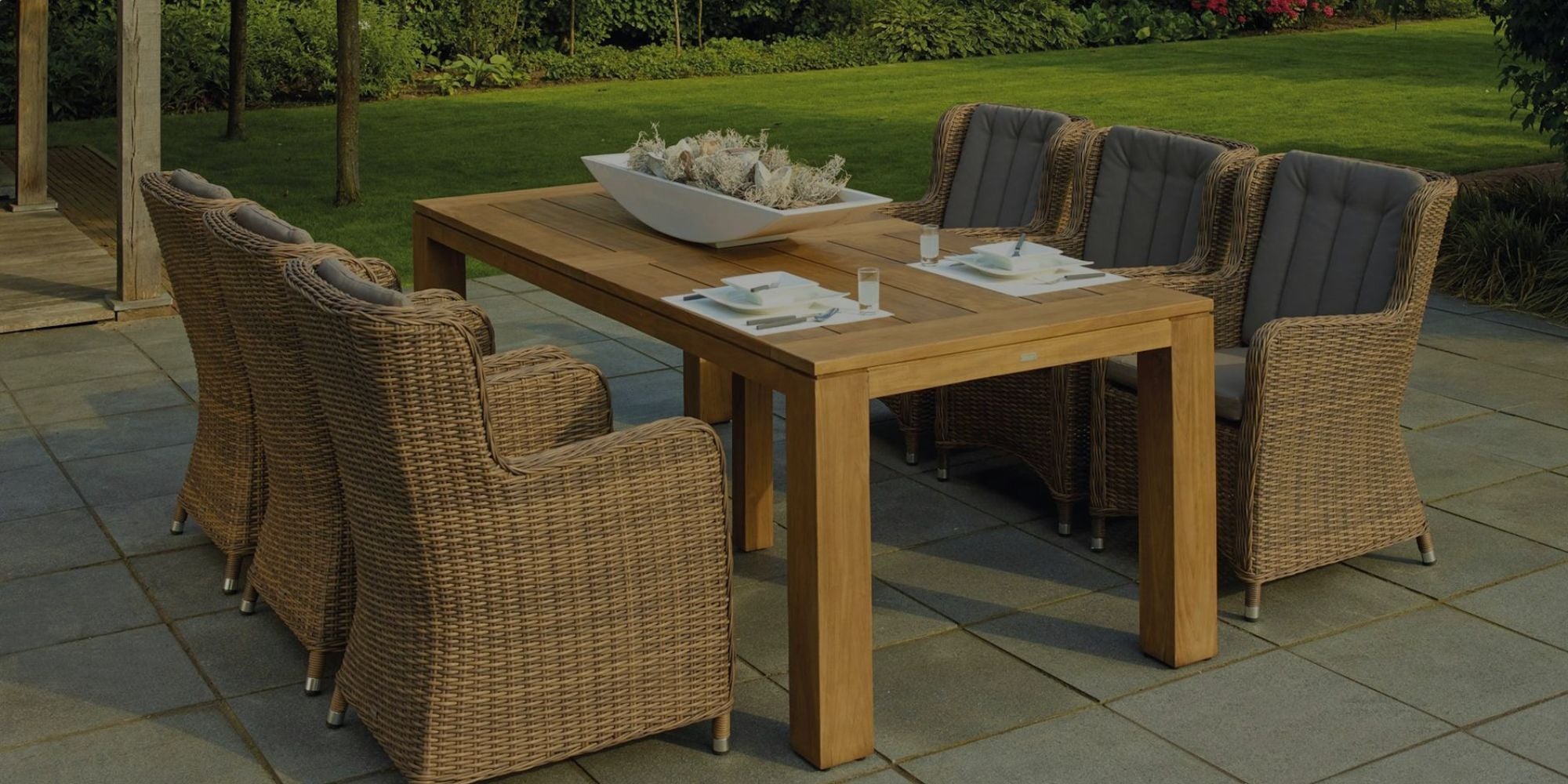 Outdoor dining set with wooden table and wicker chairs on a patio.