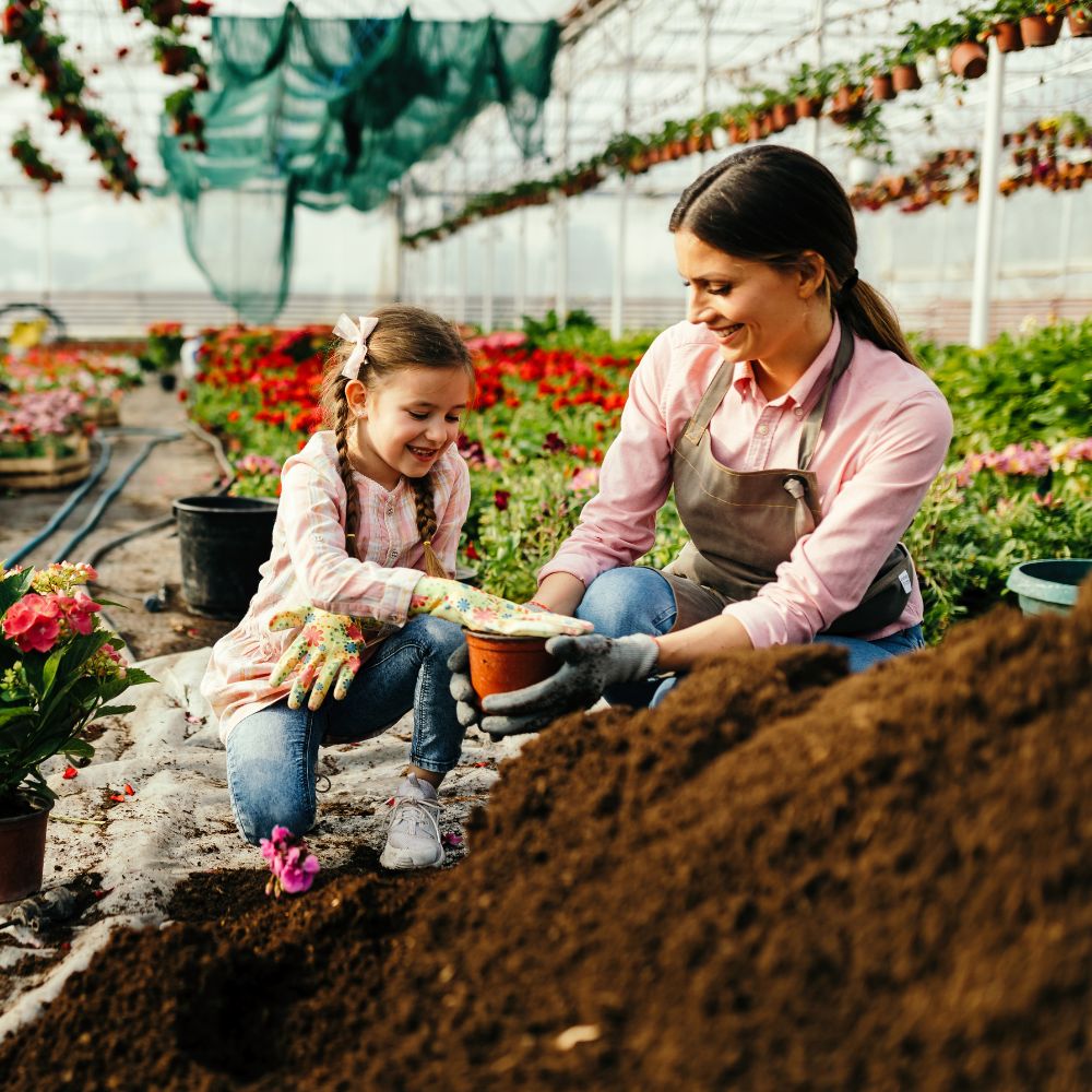 Woman and child in a greenhouse tending to plants